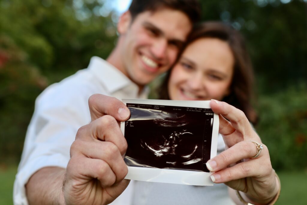 Couple holding an ultrasound scan showing early pregnancy after IVF and Frozen Embryo Transfer (FET), highlighting early pregnancy symptoms and week-by-week IVF milestones.